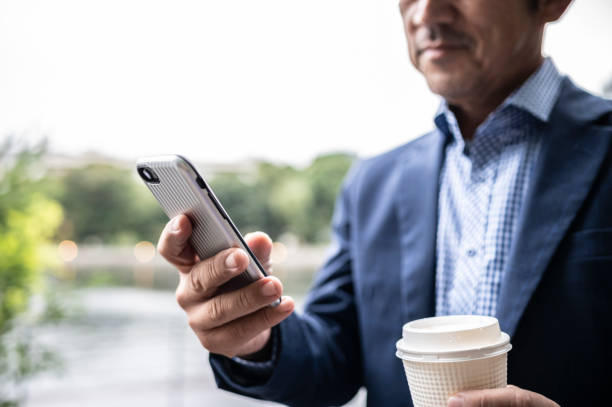 istock Businessman in a suit  texting on his smartphone in a park 1478320243