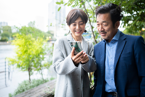Smiling middle-aged couple in formal wear checking a smartphone