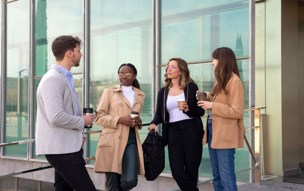 istock A group of four people standing drinking coffee talking and discussing strategy outside an office building. 1478320702