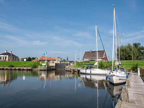 WORKUM, NETHERLANDS - SEP 14, 2021: View of lock Zeesluis and jetty with sailboats from Het Zool canal, Workum, Friesland