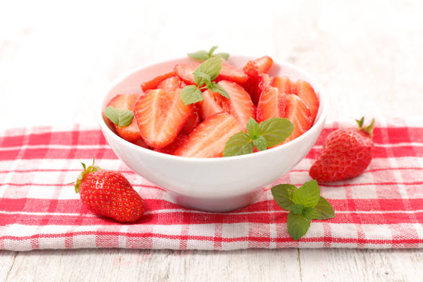 Fresh cut strawberries in white bowl isolated on white background