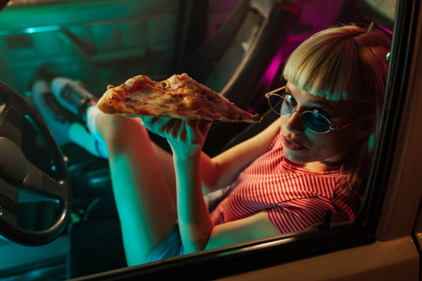 istock Girl eating pizza in car. 1478324873