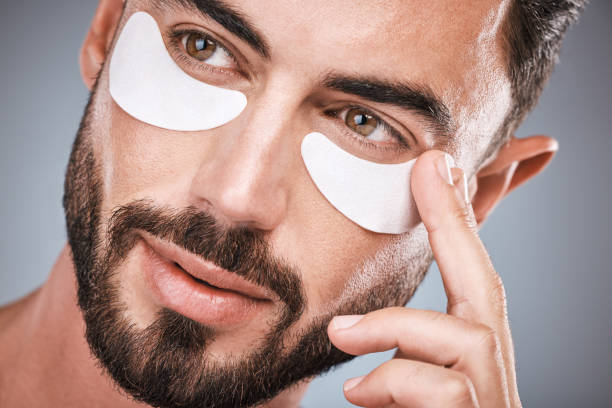 Face, man and skincare eye patches in studio isolated on a gray background for wellness. Thinking, beauty dermatology and male model apply eyes mask, cosmetics or facial treatment for healthy skin. parches oculares para la cara, el hombre y el cuidado de la piel en el estudio aislados sobre un fondo gris para el bienestar. pensamiento, dermatología de belleza y modelo masculino aplicar mascarilla ojos, cosméticos o tratamiento facial para una piel