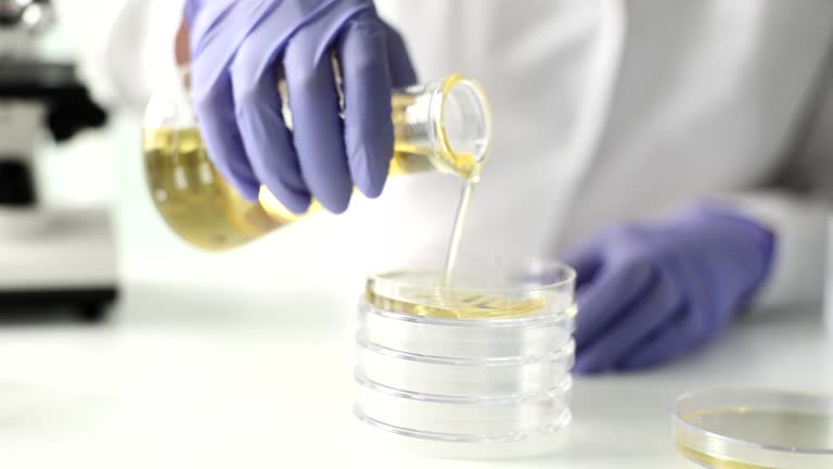 Hand pours yellow liquid into test tube closeup