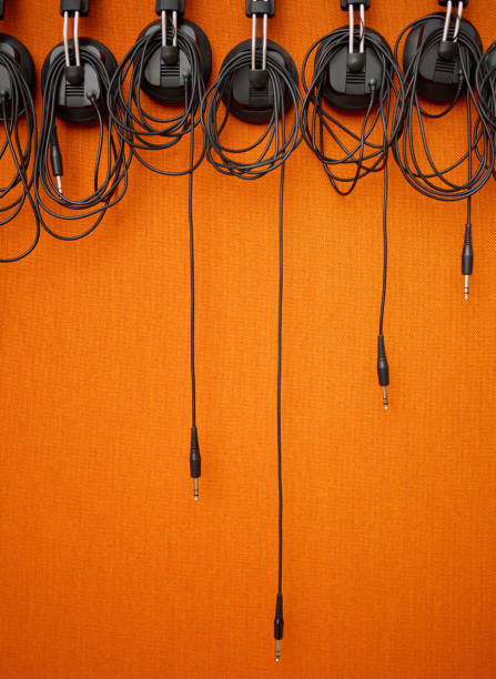 audio, cables and mockup on an orange wall background in a music studio for recording or sound engineering. media, equipment and hanging wires in an empty room of a record label for production - recording studio sound recording equipment record interconnect imagens e fotografias de stock