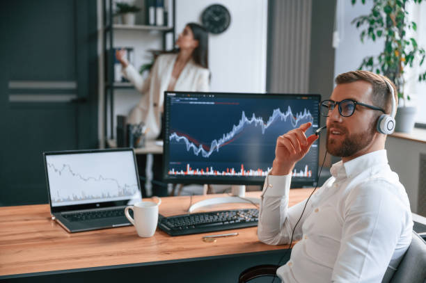 istock Exchange graphs on the screen. Two employees are working together in the modern office 1478328100