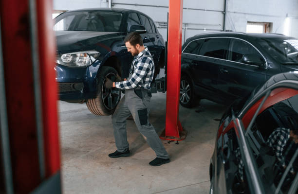 istock Front left wheel is changing. Man in uniform is working in the auto salon 1478340453