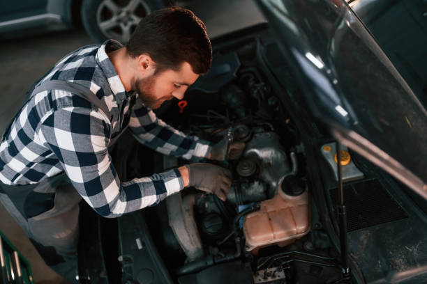 istock Using the tool and fixing the car. Man in uniform is working in the auto salon 1478340501