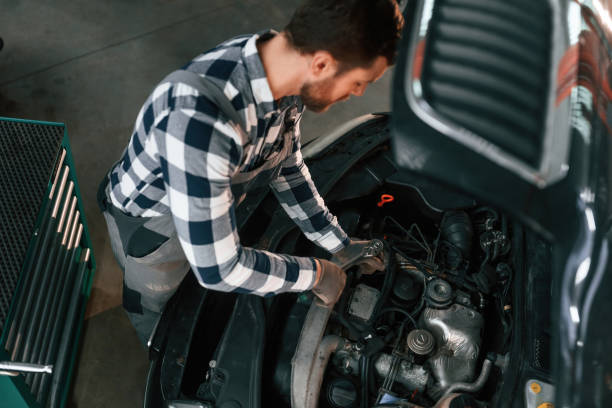 istock Using the tool and fixing the car. Man in uniform is working in the auto salon 1478340504