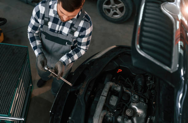 istock Using the tool and fixing the car. Man in uniform is working in the auto salon 1478340512