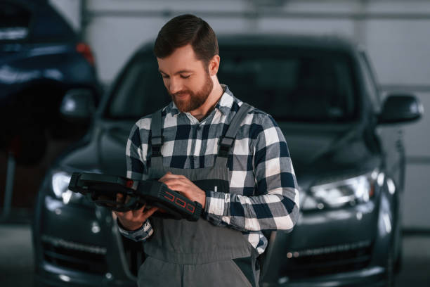 istock Holding tablet. Man in uniform is working in the auto salon 1478344319