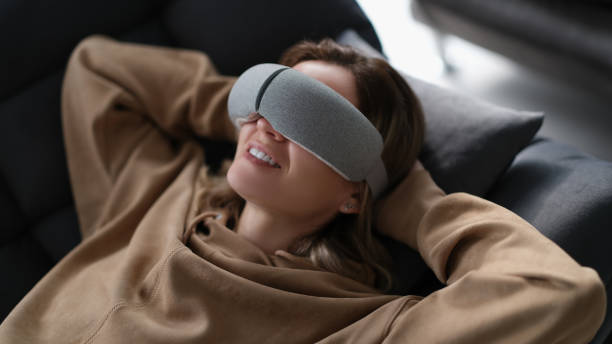 istock Woman with eye massage device lying on sofa 1478347272
