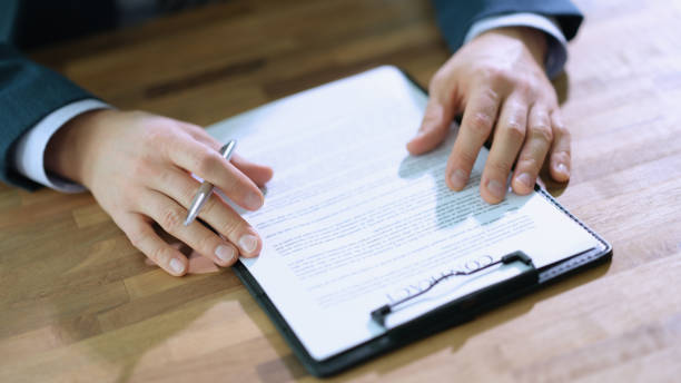 istock Businessman with pen in hands studying contract at table in office closeup 1478348480