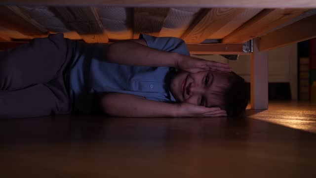 boy playing hide and seek under the bed