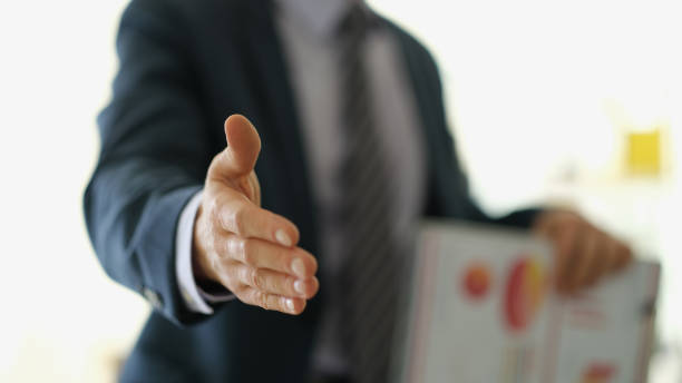 istock Businessman in suit with documents extending hand to partner for handshake closeup 1478349076