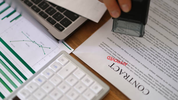 istock Director hand putting stamp approved in red ink on contract document closeup 1478349107