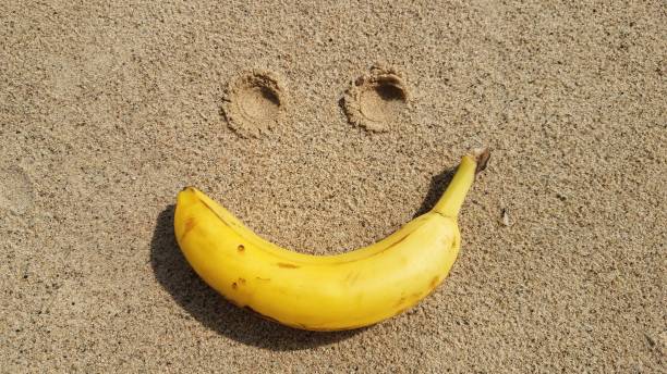 Smiling Face - Yellow Banana on the Sand Background