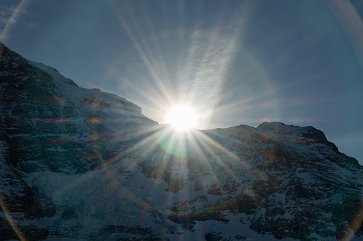 Eigergletscher, Canton Bern, Switzerland, February 11, 2023 Sun is rising behind a summit of the snow covered alps