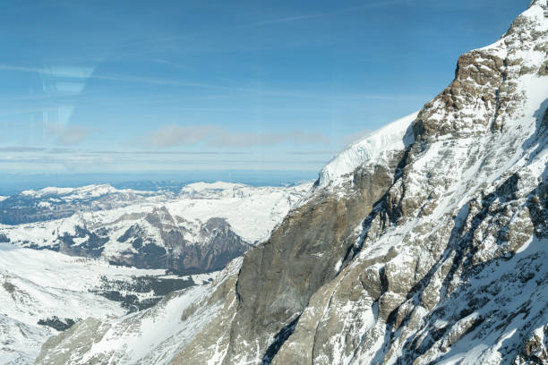 Eigergletscher, Canton Bern, Switzerland, February 11, 2023 Incredible beautiful view over the snow covered alps on a sunny day shot is taken through a window