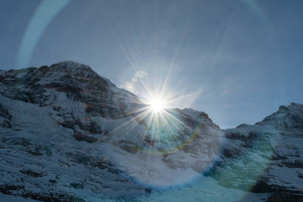 Eigergletscher, Canton Bern, Switzerland, February 11, 2023 Sun is rising behind a summit of the snow covered alps