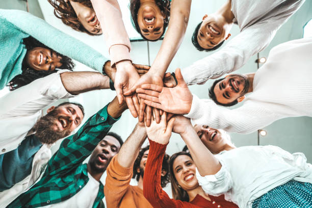 multicultural group of people stacking hands together - university students putting their hands on top of each other - human relationship, social, community, startup, teambuilding and college concept - team human hand cheerful close up imagens e fotografias de stock