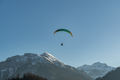 Interlaken, Switzerland, February 10, 2023 Parachute is landing on a green field in the city center