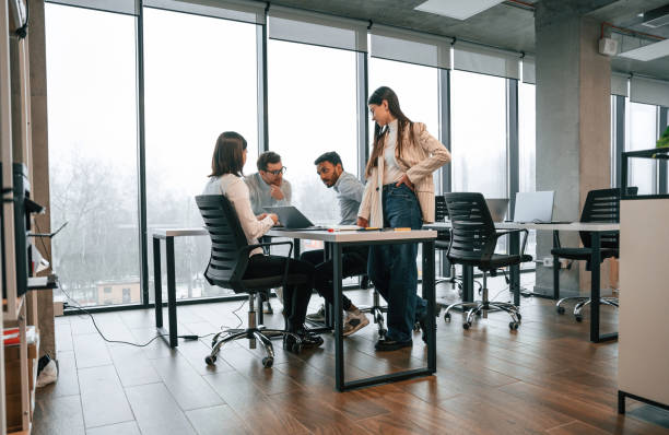 istock Against big windows by the table. Four people are working in the office together 1478357135