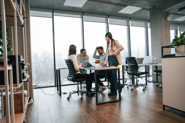 istock Against big windows by the table. Four people are working in the office together 1478357147