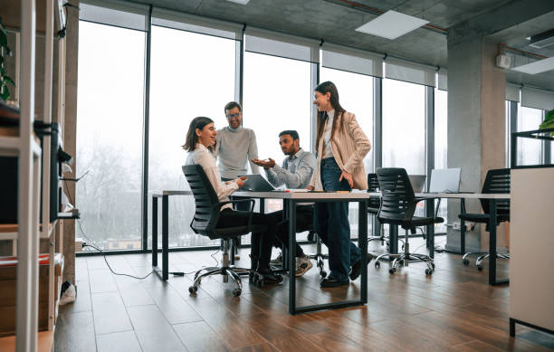 istock Against big windows by the table. Four people are working in the office together 1478357148