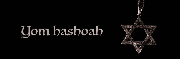 the text Yom Hashoah and an old and rusty pendant in the shape of the star of David on a black background, in a panoramic format to use as web banner