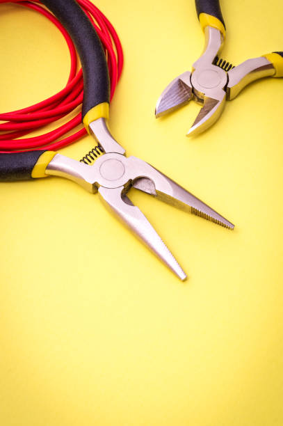 istock Electrician tool and red wire on yellow background for repairing energized systems or communications 1478360633