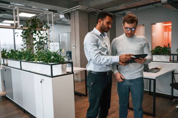 istock Information in the tablet. Two men are working in the modern office together 1478363307