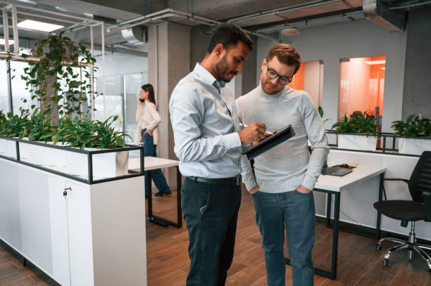 istock Information in the tablet. Two men are working in the modern office together 1478363355