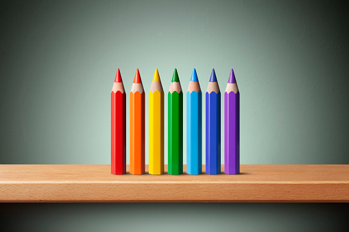 Rainbow colored pencils on the shelf.