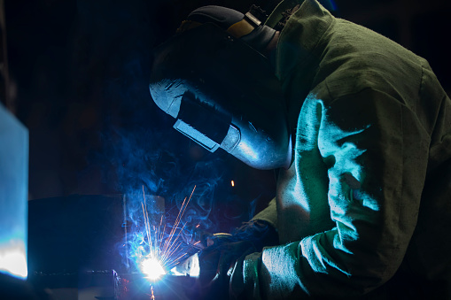 A worker in a welding suit Welding work with flying sparks.