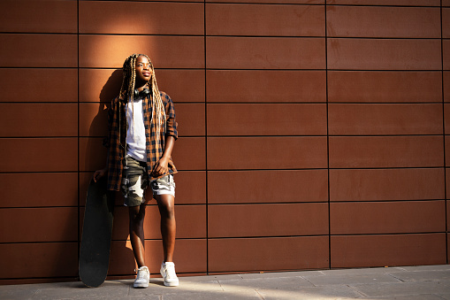 African-american woman with skateboard. Young stylish woman with skateboard outdoors