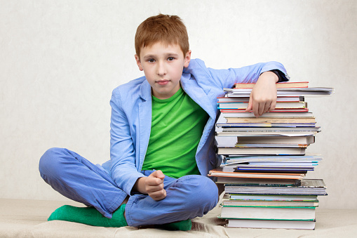 A middle school boy leaned on a stack of books.