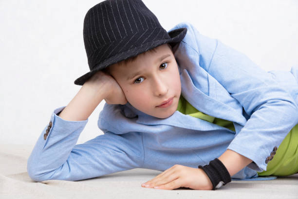 A handsome boy in a jacket and black hat looks at the camera.