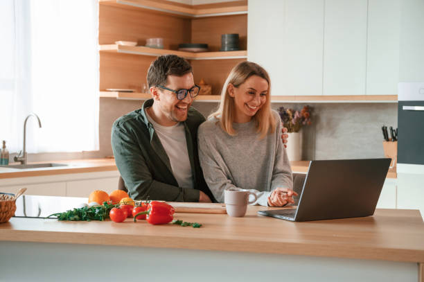 istock Sitting, using laptop. Young couple is on the kitchen together 1478368974