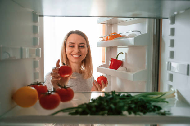 istock Taking the vegetables from fridge. Beautiful young woman is on the kitchen 1478370410