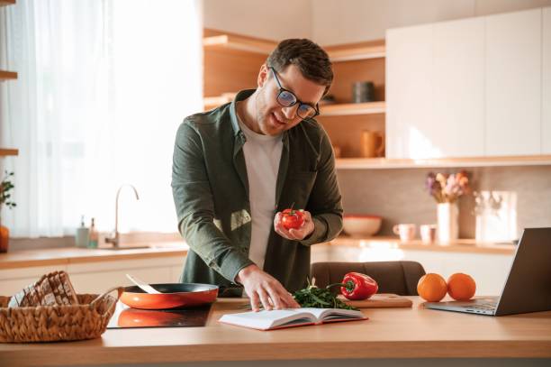 istock Reading receipt and holding tomato. Handsome man is on the kitchen at daytime 1478370607