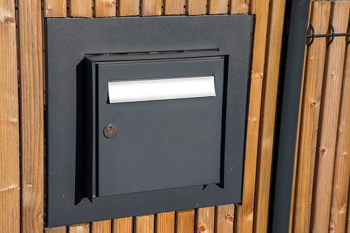 Black dark grey metal letter box gray on modern wooden fence outdoors