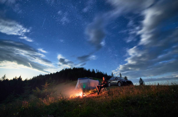 istock Young man relaxing next to bonfire on hill. 1478372534