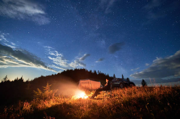 istock Young man relaxing next to bonfire on hill. 1478372549