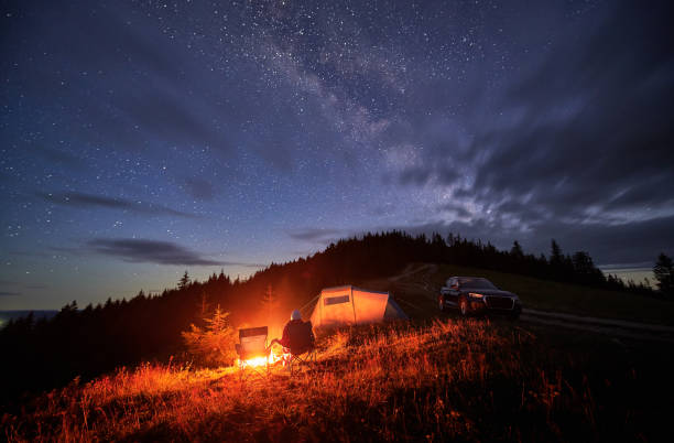 istock Young man relaxing next to bonfire on hill. 1478372575