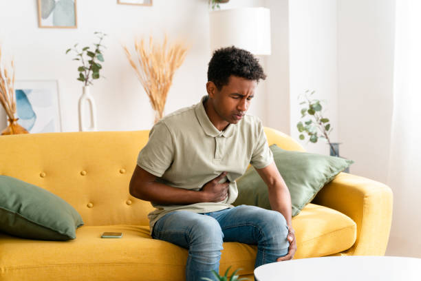 istock Black man sitting on sofa. stomach pain 1478374631