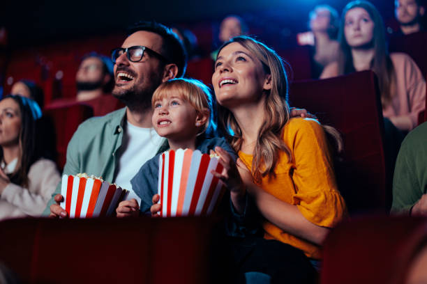 Joyful family watching movie in cinema. A young joyful couple is with their daughter in the cinema, watching an exciting movie. cinema stock pictures, royalty-free photos & images