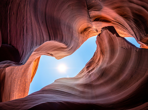 Low angle view from inside the Lower Antelope Slot Canyon in Page with the sun in the sky, Arizona. USA
