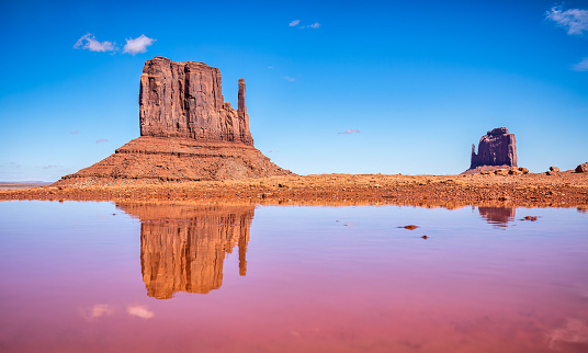 West and East Mitten Butte reflected in red water at Monument Valley tribal park, Arizona. USA