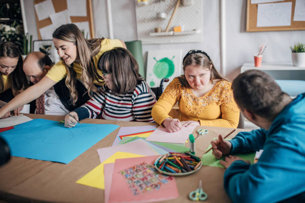 istock People with down syndrome and cerebral palsy doing an art project with help with assistants and animators.Disability health care art workshop. 1478378676